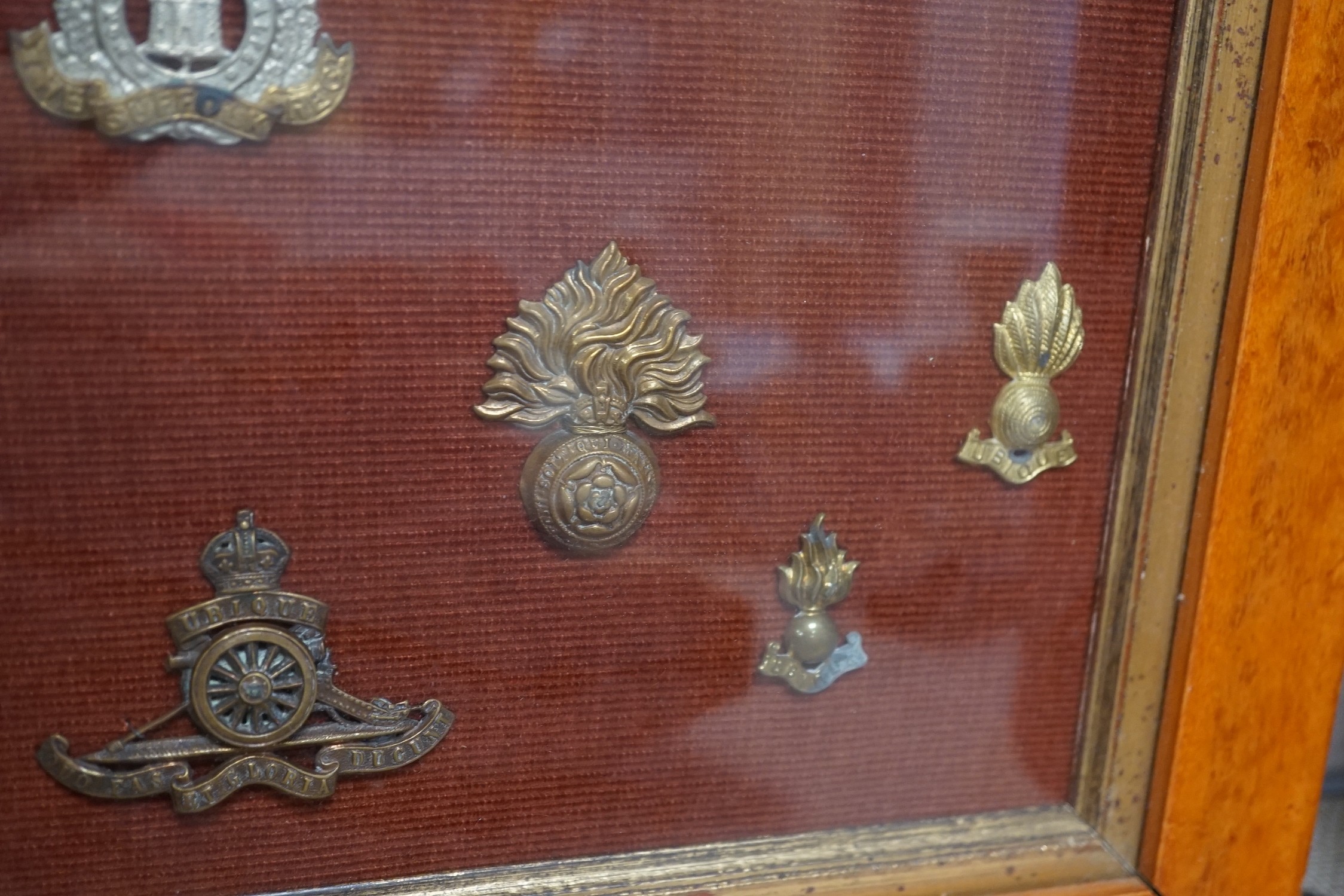 A framed collection of military cap Badges